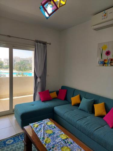 a living room with a blue couch with colorful pillows at Amwaj North coast chalet in 1st floor families only in El Alamein