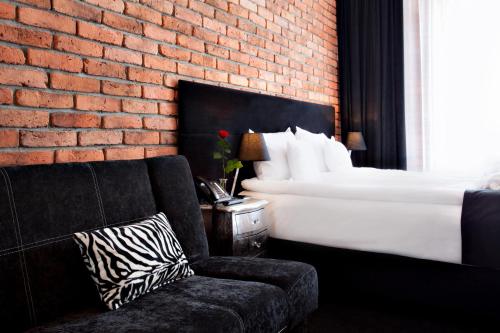 a bedroom with a bed and a couch and a brick wall at Hotel Betmanowska Main Square Residence Adults Only in Kraków