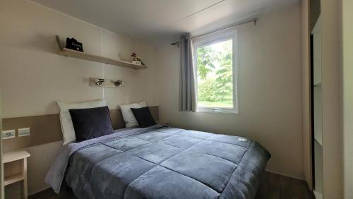 a bedroom with a large bed with a window at MobilHome Marie EUROPAPARK 20min in Boofzheim