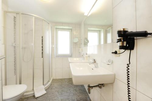 Baño blanco con lavabo y espejo en Aktiv-Ferienwohnungen Montafon, en Sankt Gallenkirch