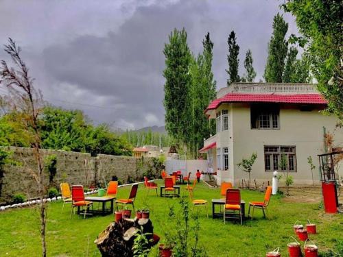 a group of chairs and tables in a yard with a house at Al Jannat Hotel & Relax Inn Guest House Skardu in Skardu