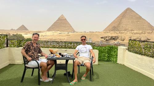 two men sitting at a table in front of the pyramids at Solima Pyramids View in Cairo