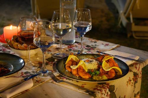 Cavomarina Beach- Adults Only في كافوس: طبق من الطعام على طاولة مع كؤوس النبيذ