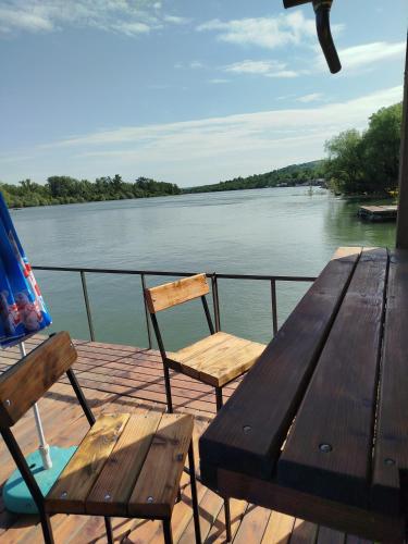 a wooden table and chairs sitting on a deck next to the water at Splav na dan AXA in Barič