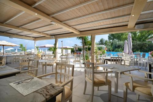 un restaurant avec des tables et des chaises ainsi qu'une piscine dans l'établissement Cavomarina Beach- Adults Only, à Kavos