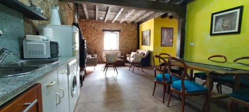 a kitchen with yellow walls and a table and chairs at Algarabiastaying 3 granja San Julián in Medina de Pomar