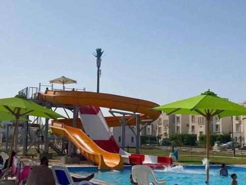a pool with a water slide and chairs and umbrellas at Amwaj North coast chalet families only in El Alamein