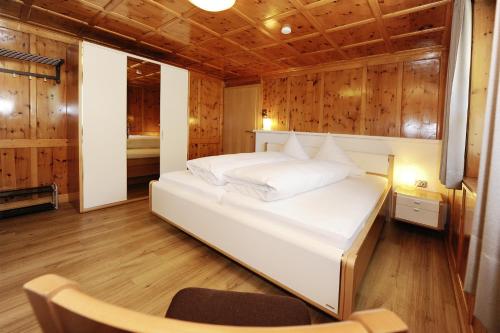 a bedroom with a white bed in a wooden room at Aktiv-Ferienwohnungen Montafon in Sankt Gallenkirch