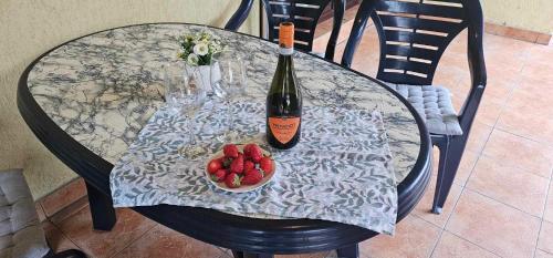 a table with a bottle of wine and a bowl of strawberries at Apartament Sorrento in Marina Cape in Aheloy