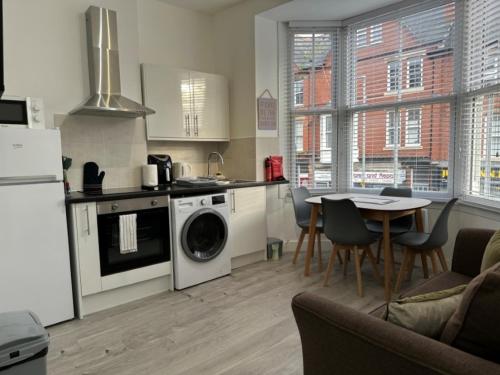 a kitchen with a washing machine and a table with chairs at Central Colwyn Bay Studio Flat 2A in Colwyn Bay