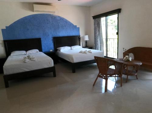 a hotel room with two beds and a table and chairs at Hotel Quinta Marciala MX in Valladolid