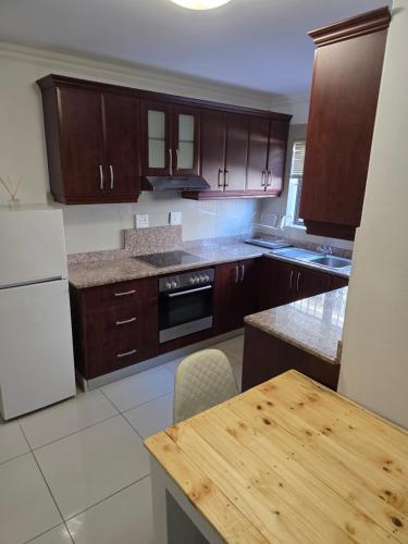 cocina con armarios de madera y mesa de madera en Durban Muslim/Halaal Accomdation, en Durban