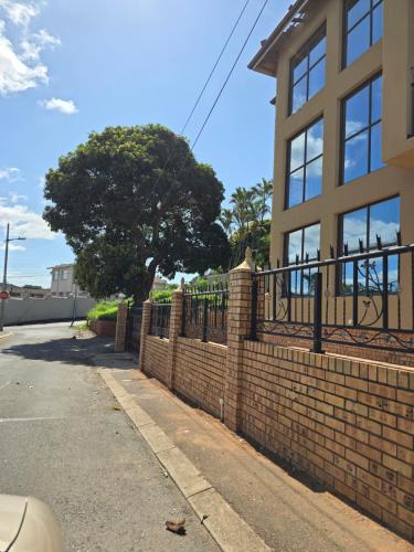 una cerca de ladrillo frente a un edificio con un árbol en Durban Muslim/Halaal Accomdation en Durban