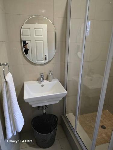 a bathroom with a sink and a shower and a mirror at Durban Overport Halaal Accomodation 5S in Durban
