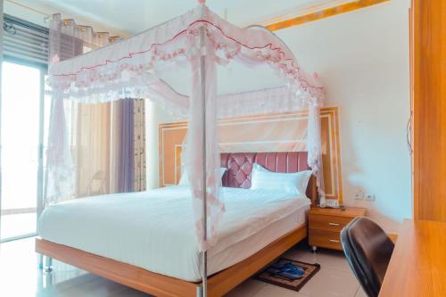 a bedroom with a canopy bed and a desk at Western Mountain Hotel in Rubavu