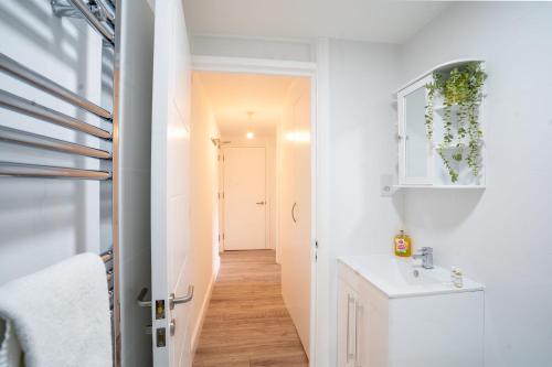 a small bathroom with a sink and a hallway at Modern Apt with Free Parking & Park Views in MK in Woolstone