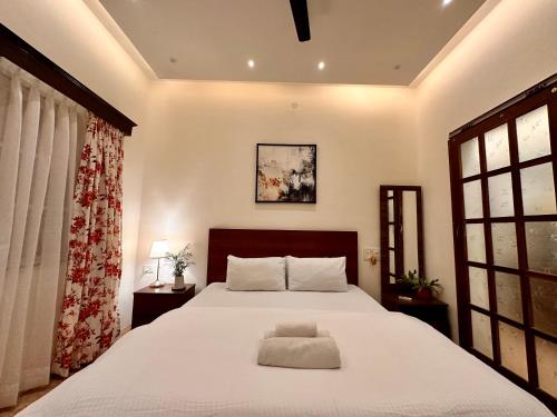 a bedroom with a large white bed and a window at Nestwood - By The Beach Goa in Benaulim