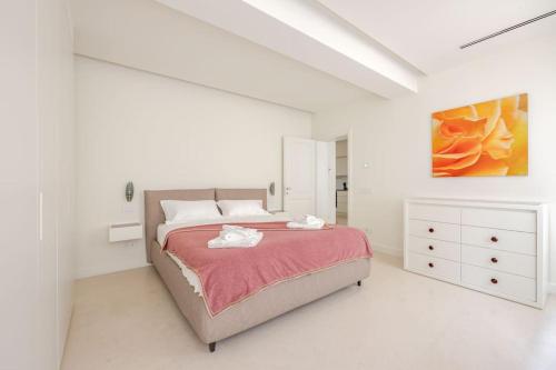 een witte slaapkamer met een bed en een schilderij bij Home In The Heart Of Ghirlandina in Modena