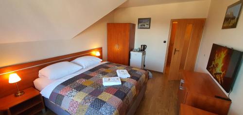 a hotel room with a bed and a television at Penzión Biela Voda in Veľká Lomnica