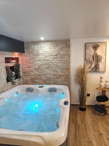 bañera de hidromasaje en una habitación con pared de ladrillo en Château de la sagesse SPA, en Rouen
