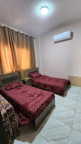 two beds in a room with red comforters at Julie Home Chalet in Madaba