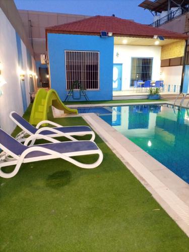 a pool with lounge chairs next to a swimming pool at Julie Home Chalet in Madaba