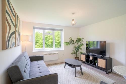 a living room with a couch and a tv at Modern Apt with Free Parking & Park Views in MK in Woolstone