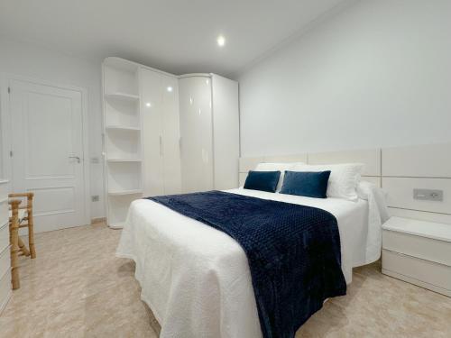 ein weißes Schlafzimmer mit einem großen Bett mit blauen Kissen in der Unterkunft Casa Baltar, Sanxenxo, a 100m de la playa de Baltar in Sanxenxo