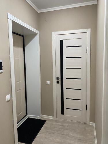um corredor com uma porta branca e um espelho em 1-комнатная комфортная кухня-студия со всеми удобствами em Qostanay