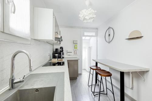 a white kitchen with a sink and bar stools at La maison du bonheur - CDG & parc des expos - piscine privée in Villepinte