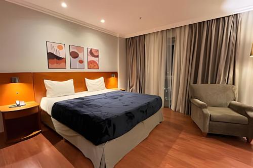 a hotel room with a bed and a chair at Flat Barra First - Morada Stay in Rio de Janeiro