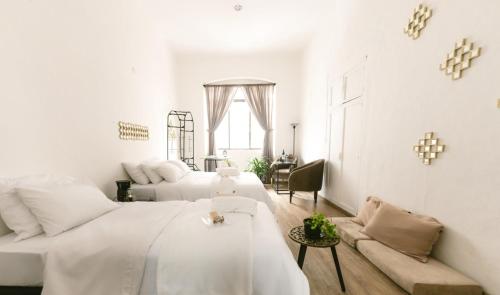 Habitación blanca con 2 camas y sofá en Suites Centro Histórico en Cuenca