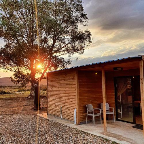 a cabin with two chairs and a table and a tree at Die Bloekomhuis in Ceres