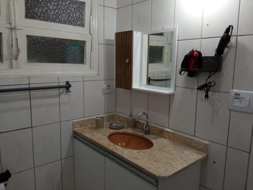 a bathroom with a sink and a mirror at Espaço Acolhedor perto da Praia. in São Vicente