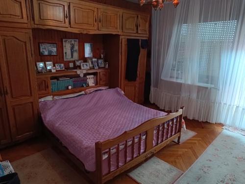 ein Schlafzimmer mit einem Holzbett mit einer lila Decke in der Unterkunft Kuća in Donja Kapija