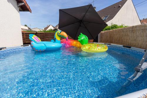 une piscine avec deux jouets gonflables et un parasol dans l'établissement La maison du bonheur - CDG & parc des expos - piscine privée, à Villepinte