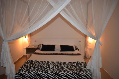 Seven Heaven do Indico في إنهامبان: غرفة نوم بسرير مع ستائر بيضاء
