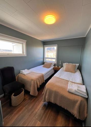 a bedroom with two beds and a chair in it at Nónhóll - Ocean View Cottage in Arnarstapi in Stapi
