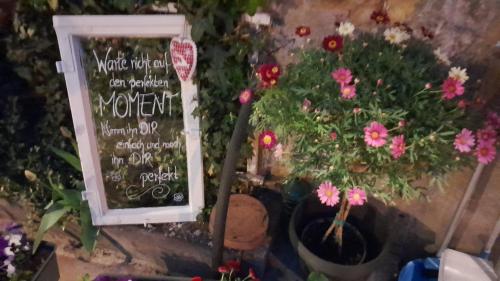 a chalkboard with a sign next to some flowers at Ferienwohnung an den Itzauen in Großheirath