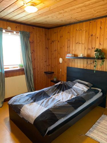 een bed in een kamer met een houten wand bij Barts house in Länshult