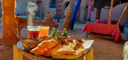 un plato de comida con pan y bebidas en una mesa en Auberge Kasbah Dar Sahara Tours, en Mhamid