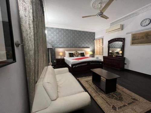 ein Wohnzimmer mit einem Bett und einem weißen Sofa in der Unterkunft Heavenly Stays in Karatschi