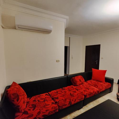 a black couch with red pillows in a room at Khamis Apartment in Amman