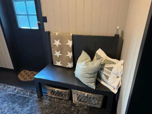 a blue bench with pillows sitting in front of a door at Nordbyhuset, et trivelig fritidshus in Skudeneshavn