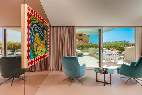 a living room with blue chairs and a large painting at Taormina Infinity Suites in Taormina