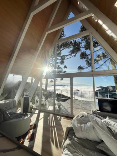 a bedroom with a view of the ocean through a large window at Chalé Aframe- Benta Rosa Chalés de Luxo in Urubici
