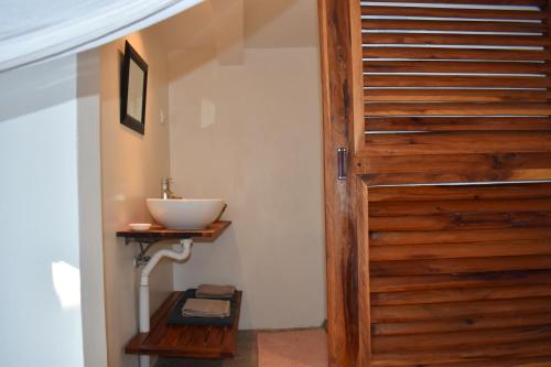 a bathroom with a wooden door and a sink at Seven Heaven do Indico in Inhambane