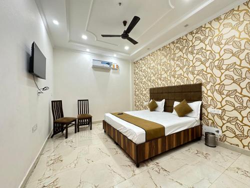 ein Schlafzimmer mit einem Bett, einem Stuhl und einem TV in der Unterkunft Embasy Hotel Near Golden Temple in Amritsar
