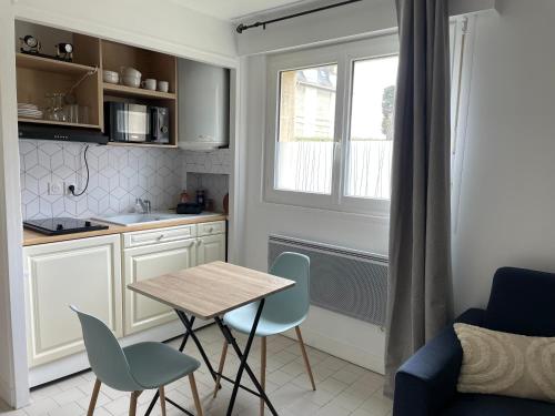 une petite cuisine avec une table et des chaises dans une pièce dans l'établissement L’Odyssée, à Blonville-sur-Mer