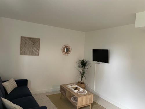 un salon avec un canapé et une télévision dans l'établissement L’Odyssée, à Blonville-sur-Mer